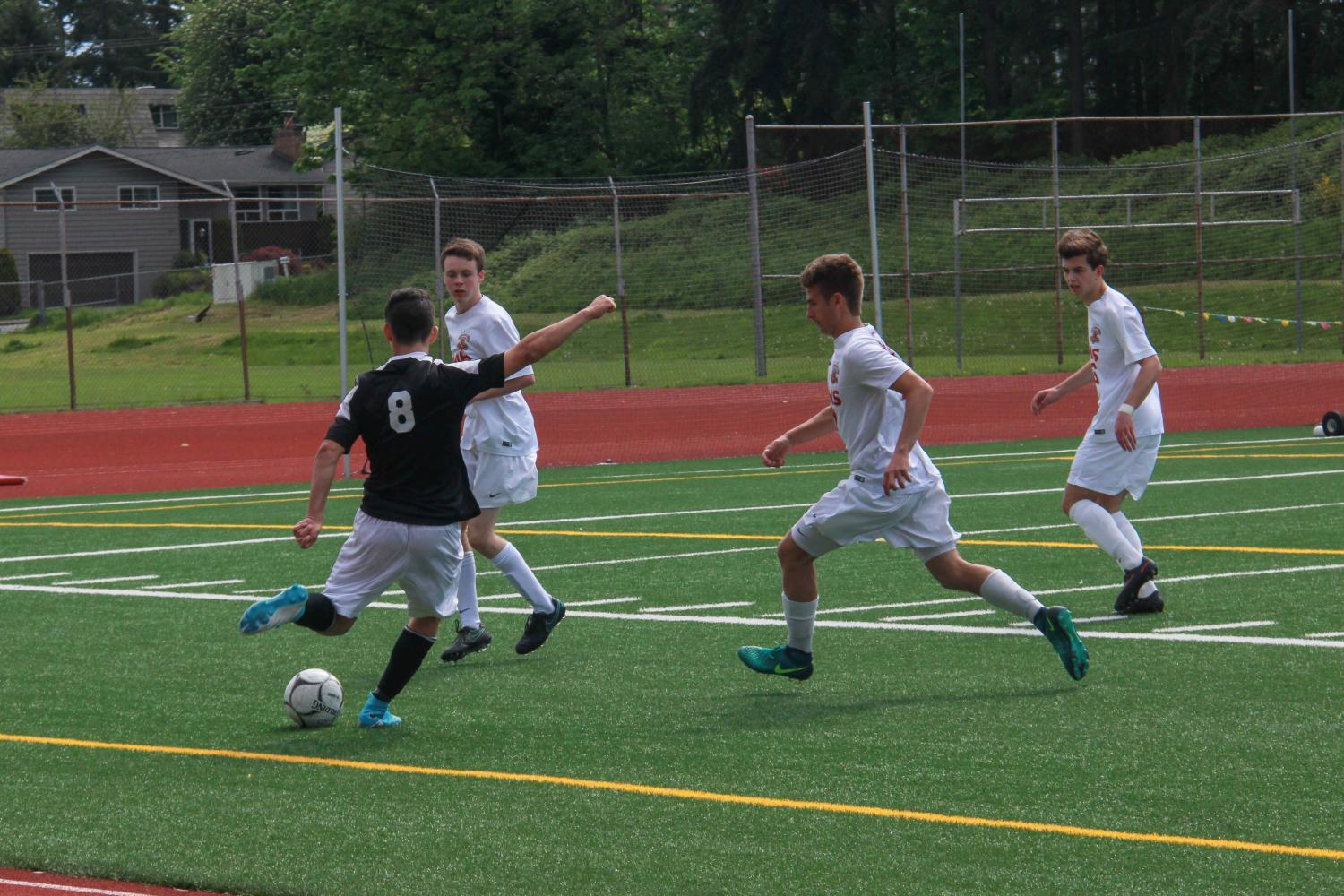 Junior forward Bobby Stoyanov attempts to kick the ball away from a crowd of approaching Wildcats.