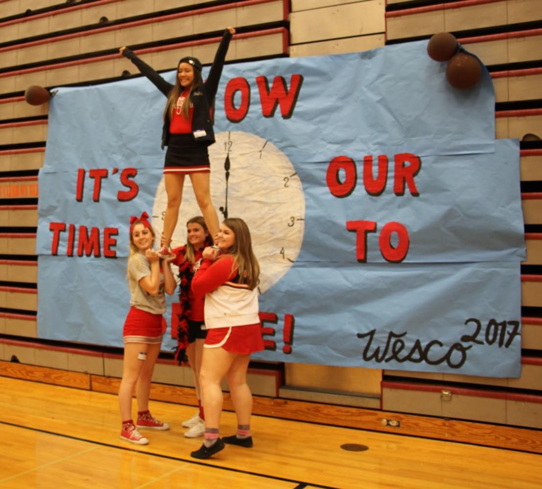 Cheerleaders pose in front of the main Wesco ASB Conference banner.  