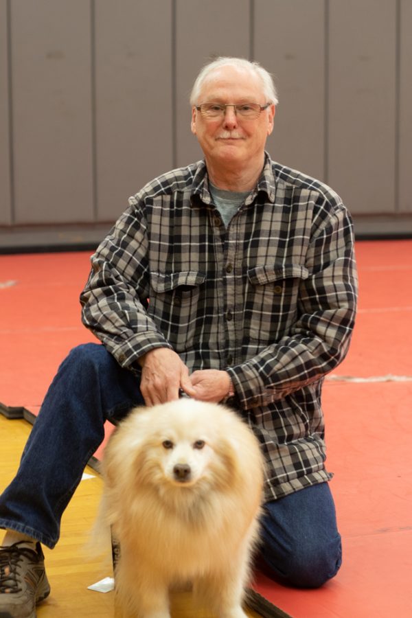 Former wrestler and Terrace alumnus Norm Buntting kneels on the wrestling mats in the Terraceum with his service dog Charlie. The pair are a common sight at wrestling matches, cheering on the current generation of competitors.