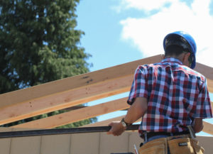 Senior Izrael Carbajal measures the roof overhang of one of the tiny houses being built by the carpentry class.