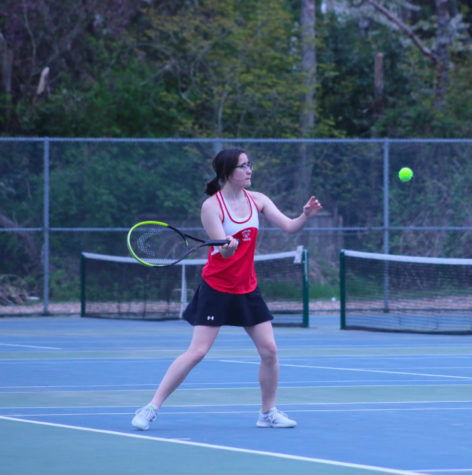 Ainsley Ward hitting a tennis ball on the courts behind MTHS.