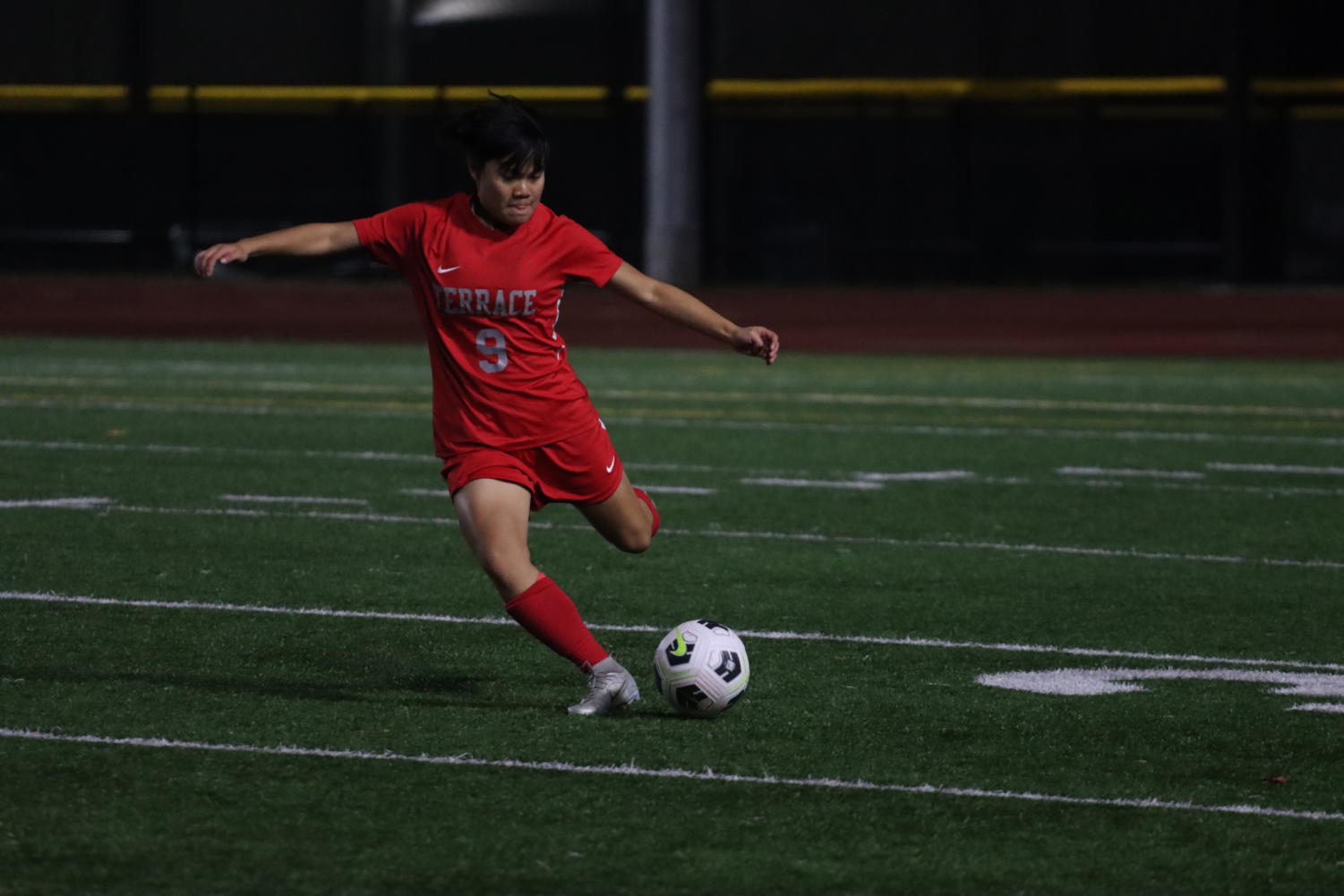 Junior Daniela Cortezzo on the field in a soccer game. Shes just about to kick the ball, with her leg lifted ready to kick.