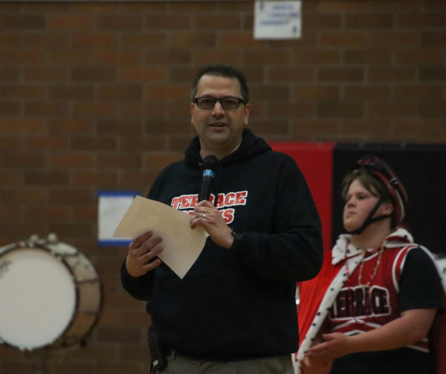 Principal Greg Schellenberg giving a speech at the winter assembly while senior Ryan Daly intently listens.