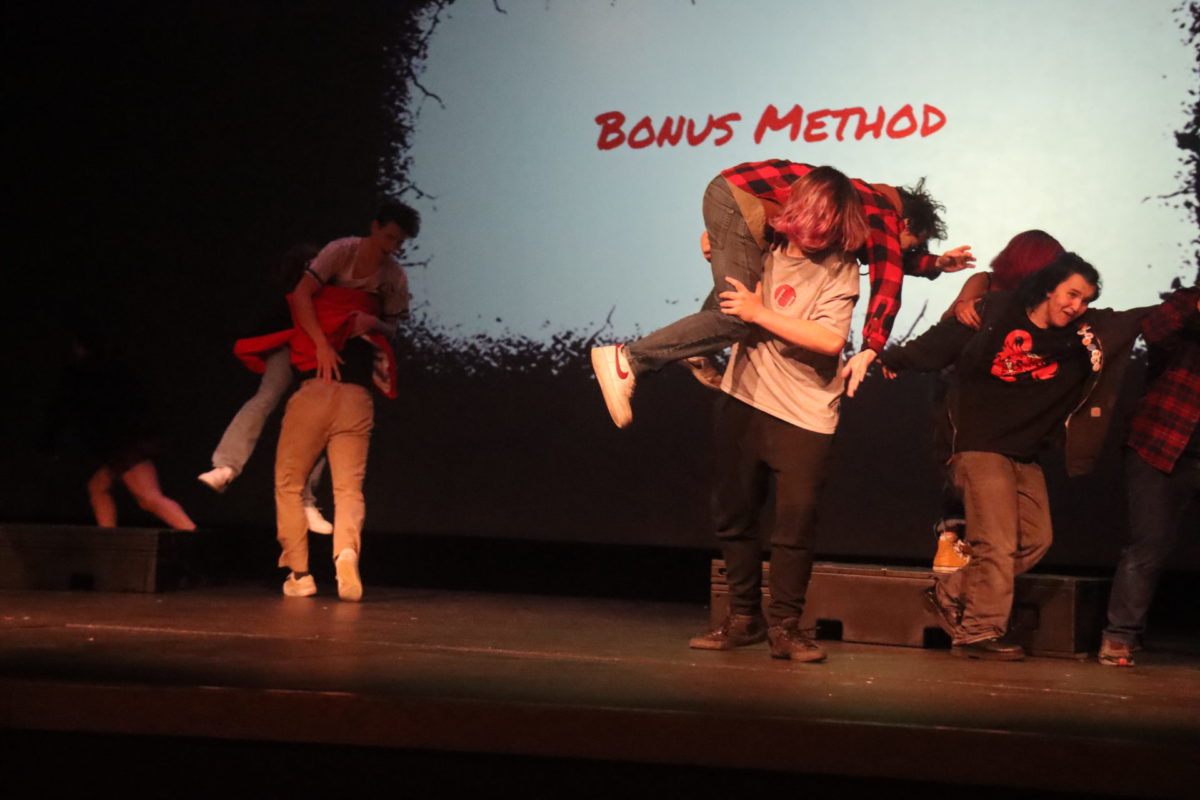 The cast of Ten Ways to Survive a Zombie Apocalypse in their last scene, Bonus Method of how to survive the upcoming apocalypse; leaving the play itself (breaking the fourth wall). Senior Collin Fahey is carried away by fellow senior, Braden Ryder, while sophomore Tate Haney is taken away by classmate J Gurney.