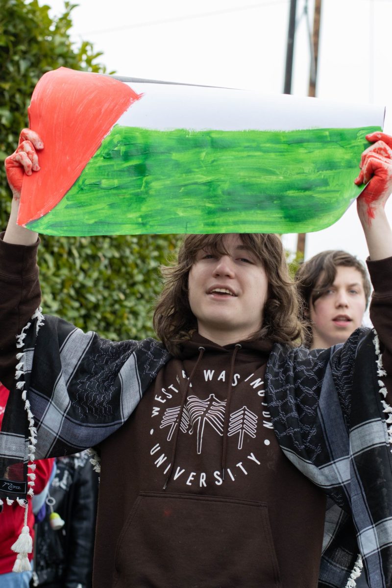 Sophomore Mariah Treadwell holds up a poster with the Palestinian flag painted onto it and red paint on her hands to represent the lives taken.