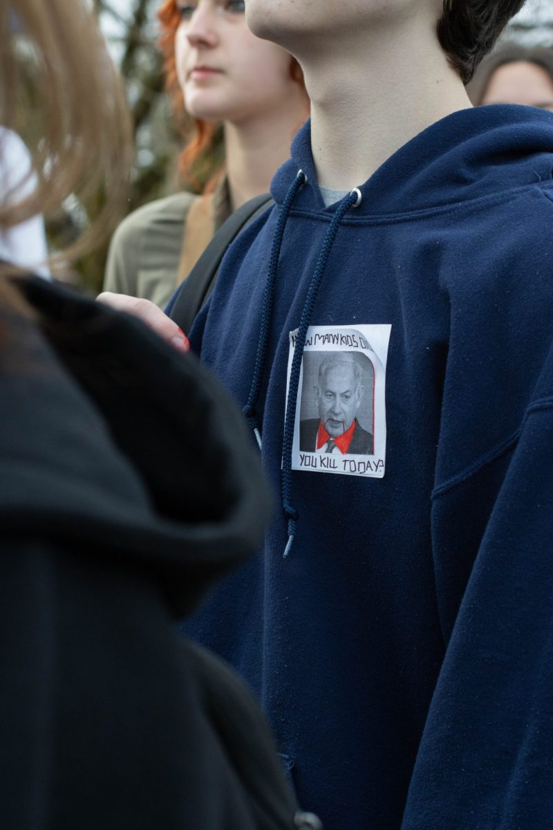 Student wears a sticker made by the protest organizer, with a photo of Israel prime minister, Benjamin Netanyahu portraying a vampire, with the label How many kids did you kill today?