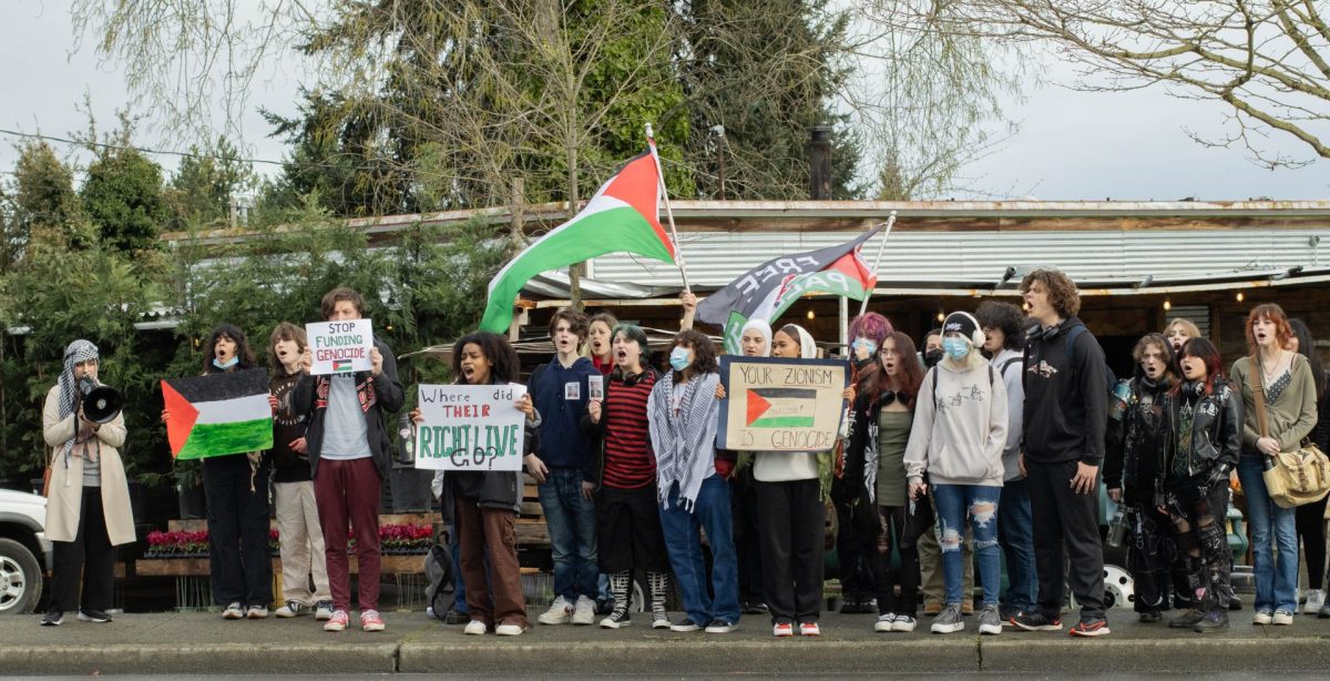 Students line up in front of Sunshine Farmers Market on 212th St, chanting and holding up their posters for support of Palestine. 