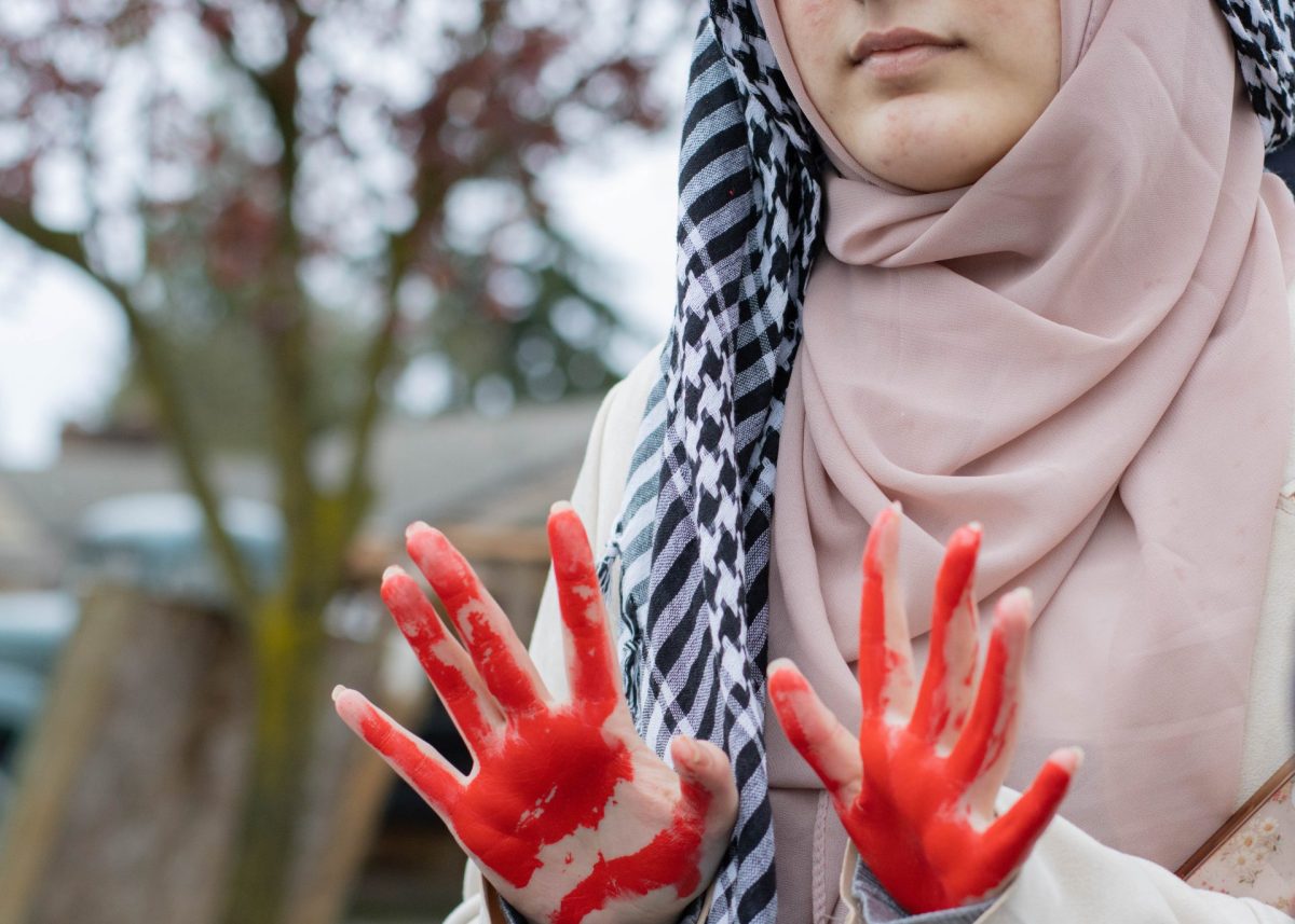 Student presents her hands painted red, representing the lives taken in Palestine. 