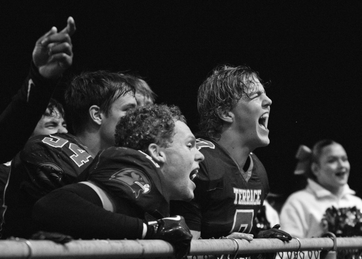 The football team, fronted by Elyjah Meegan (4) and Andrew McBride, cheer to the student section after a homecoming victory.
