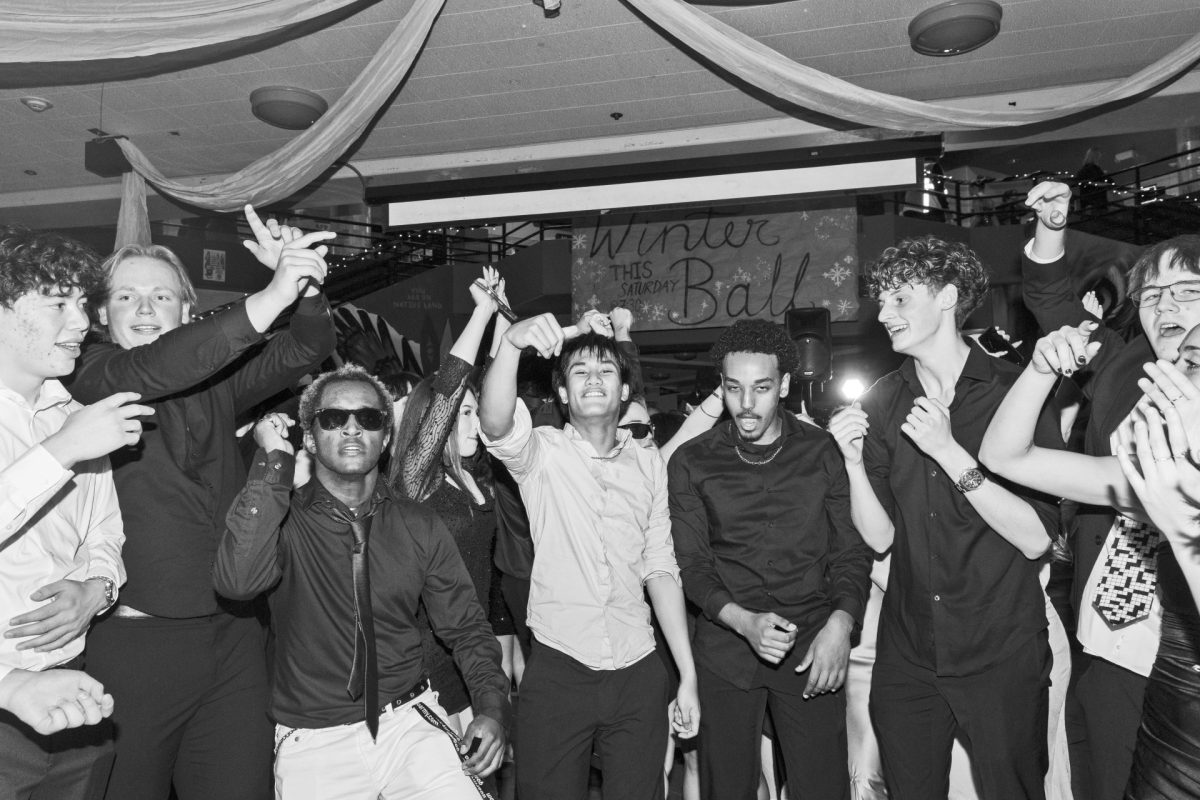 Attendees of the Winter Ball fill the dance floor while the DJ plays music.  
