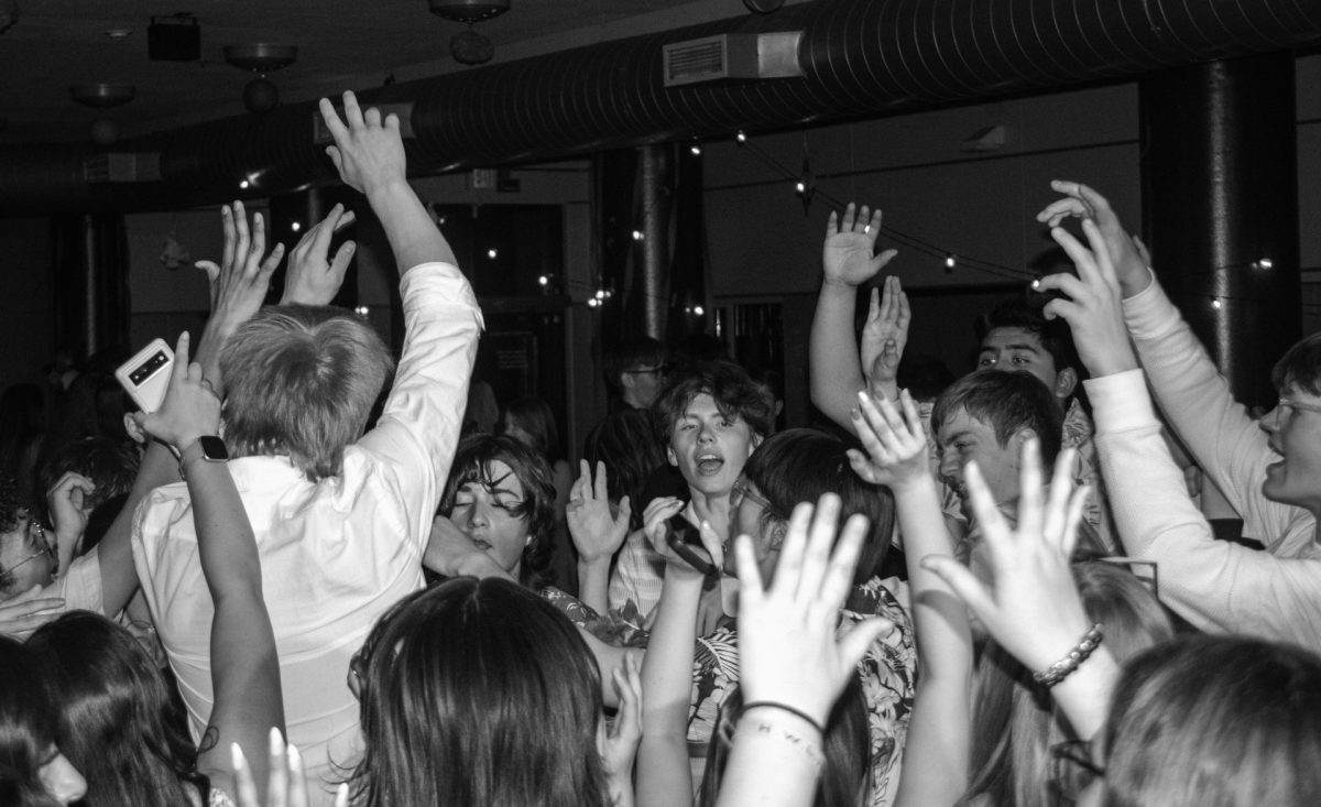 Schaeffer and a group of students raising the energy to the roof with their hands in the air at the Spring Fling. 